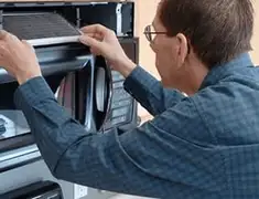 Appliance repair technician replacing a microwave vent filter in Cambridge, MA