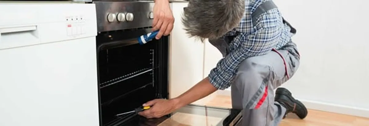 Oven repair technician inspecting and servicing an electric oven in Cambridge, MA