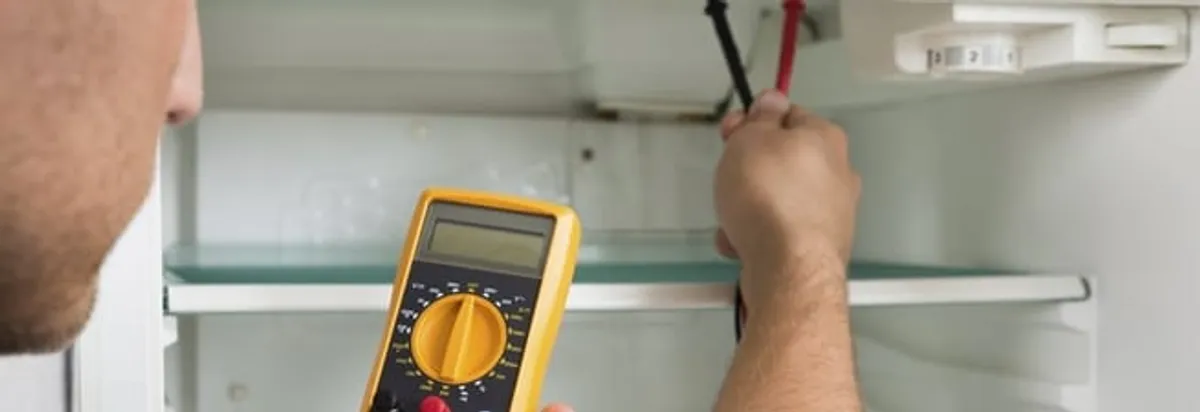 Refrigerator repair technician testing electrical components with a multimeter in Cambridge, MA