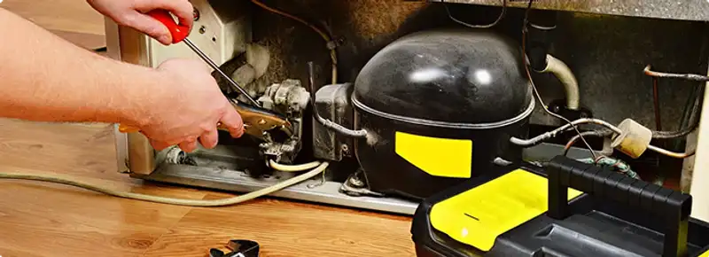 Refrigerator repair technician fixing the compressor and wiring in Cambridge, MA